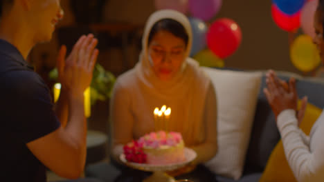 Multi-Cultural-Friends-Giving-Woman-Birthday-Cake-With-Candles-At-Party-At-Home-1